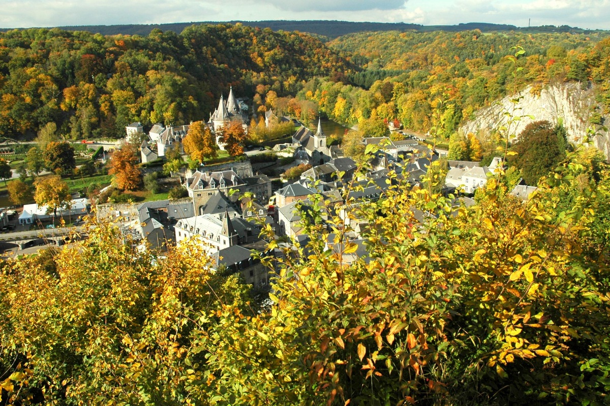 Durbuy’s stone houses and church surrounded by wooded hills in autumn