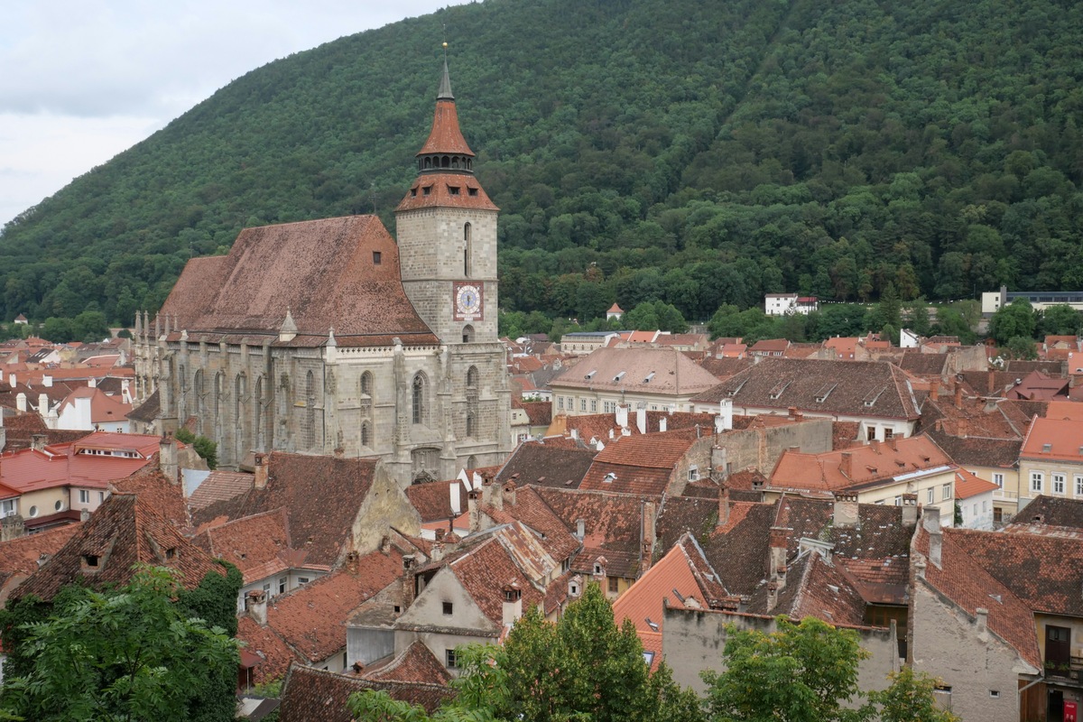 Brașov’s Black Church above red-roofed buildings with a forested hillside behind