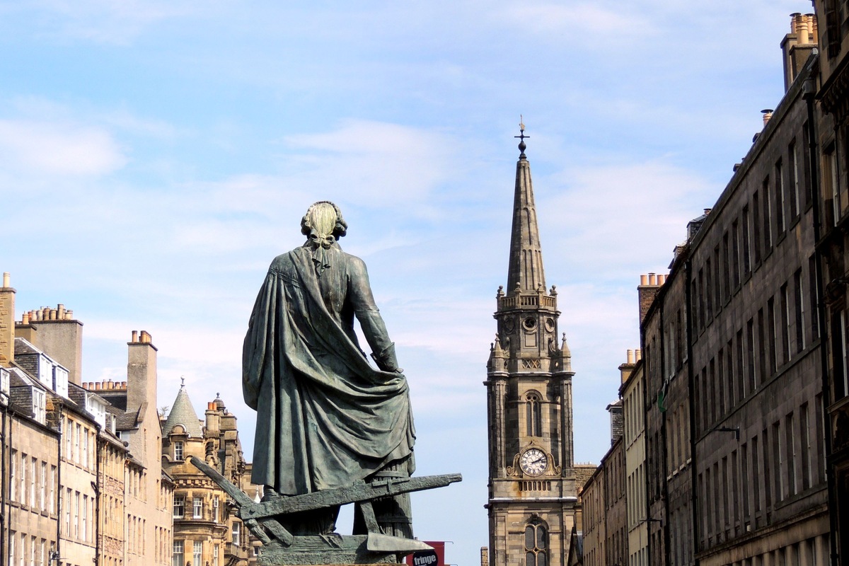 A statue and historic stone buildings along Edinburgh’s Royal Mile beneath a blue sky