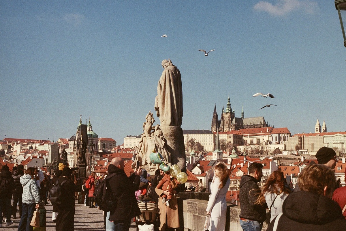 Visitors on Charles Bridge with Prague Castle and St Vitus Cathedral across the river