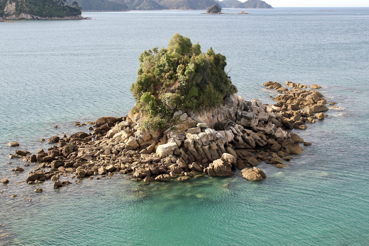 Rocky islet in clear turquoise water near Pitt Head in Abel Tasman National Park