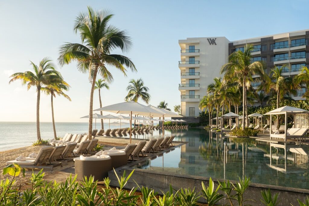 Waldorf Astoria Riviera Maya swimming pool, palm trees and beachfront in Mexico on a sunny day